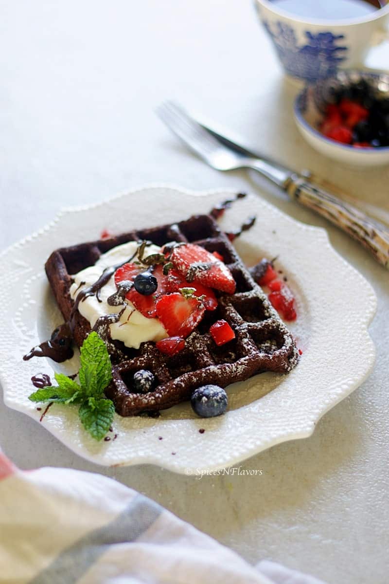 eggless chocolate waffles topped with whipped cream and berries