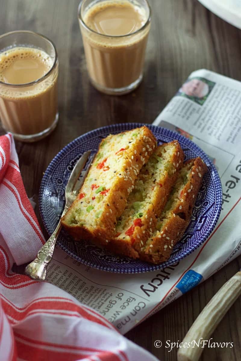 3 slices of cake placed on a blue plate alongwith a newspaper and tea in the background