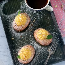 vertical image of lemon friands with lemon curd on top