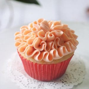 strawberry filled cupcake with a ruffle pattern placed on a small white lace dollie