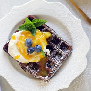 chocolate waffles topped with whipped cream and passionfruit mango compote