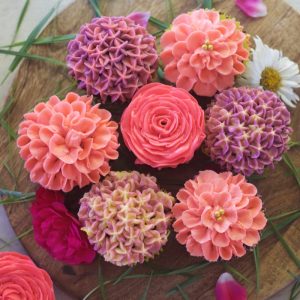 close up view of 7 buttercream flowers placed adjacent to each other forming circle