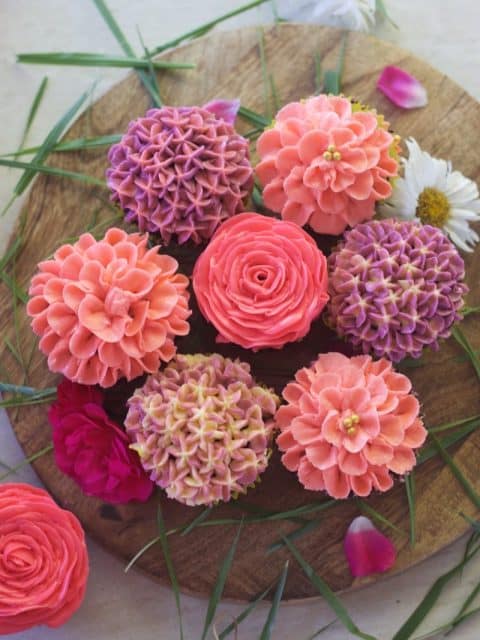 close up view of 7 buttercream flowers placed adjacent to each other forming circle