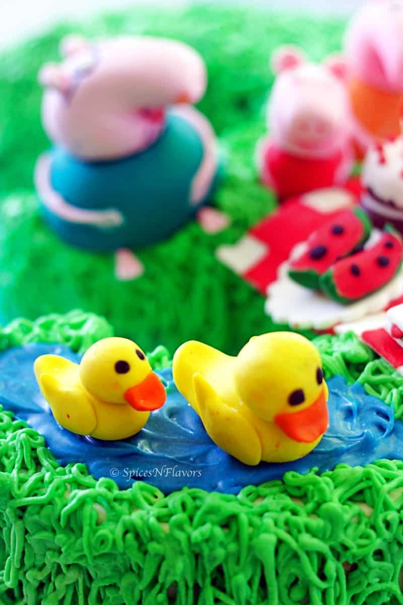 image showing fondant accents of peppa pig and family along with picnic basket placed on peppa pig birthday cake