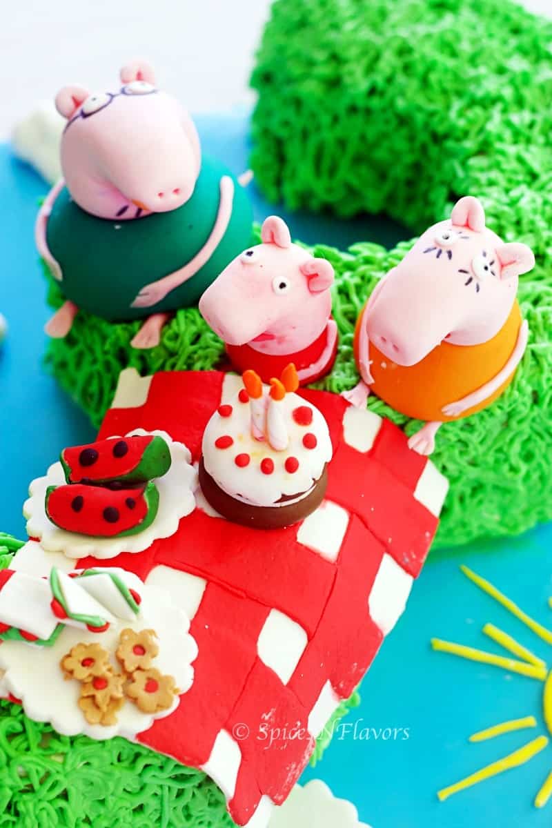 image showing fondant accents of peppa pig and family along with picnic basket placed on peppa pig birthday cake