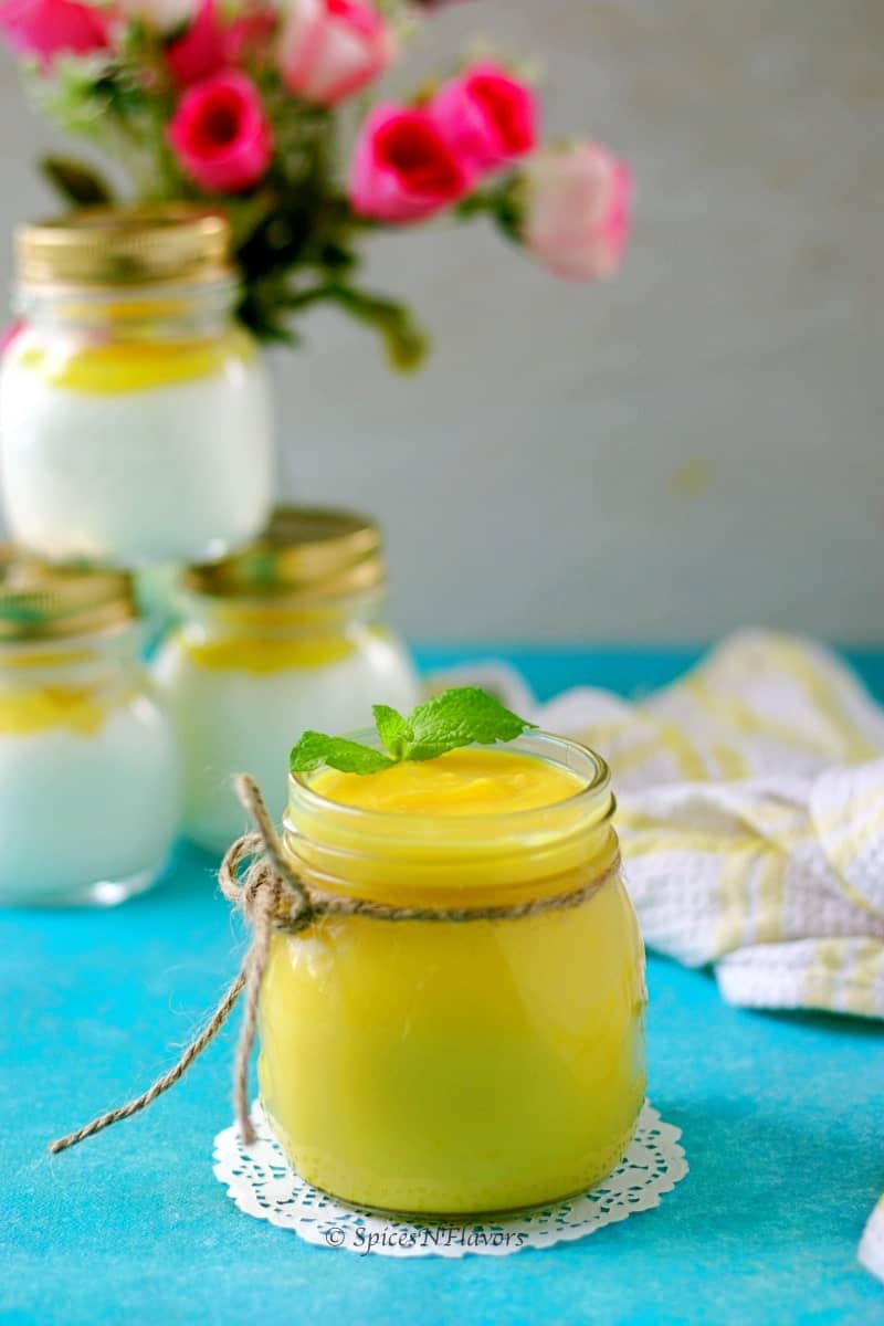 straight image of instant pot lemon curd with yogurt jars and flowers in background