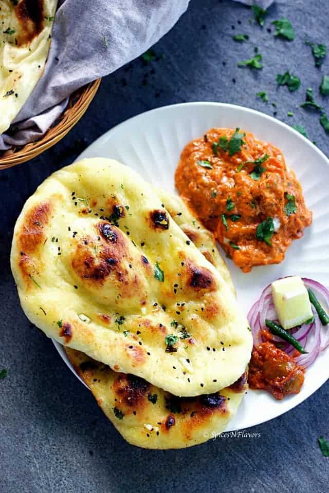 naan bread served in a round plate with curry and onions on the side