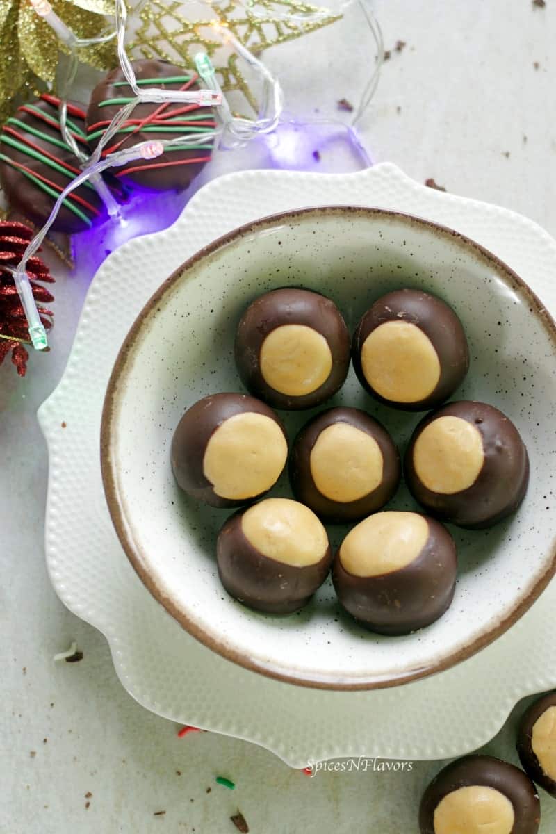 buckeyes aka peanut butter balls placed in a circular white bowl surrounded with christmas decorations