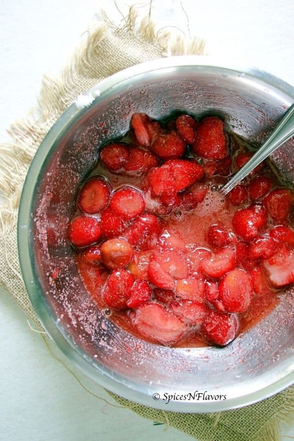 frozen strawberries macerated in sugar in a mixing bowl