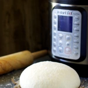 proofed bread dough placed on a towel with a rolling pin and instant pot in the background