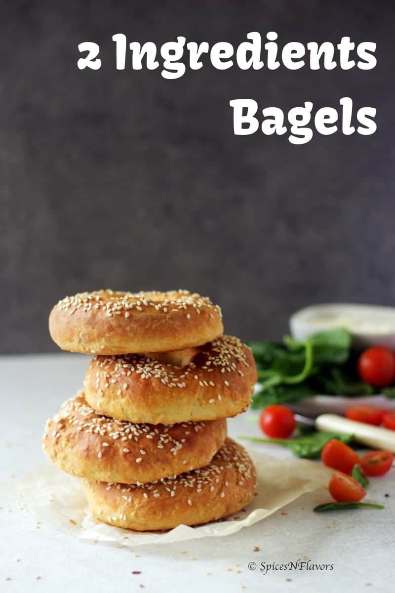 bagels placed one on top of other with spinach and tomatoes in the backgroup