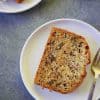 close up overhead image of banana bread slice placed on a white plate with a fork on the side