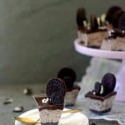 Oreo mousse cups placed on a white plate with a golden spoon on the side