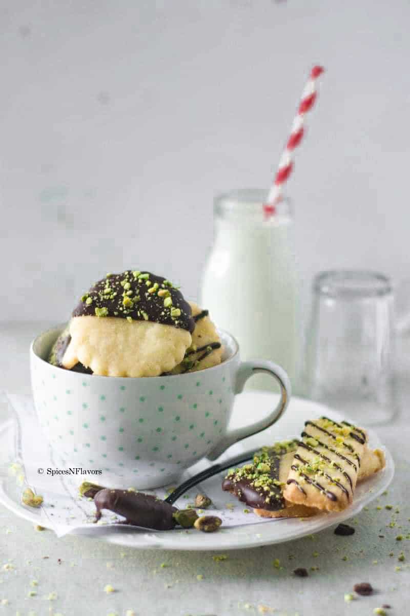chocolate dipped cookies placed on a tea cup with milk in the background