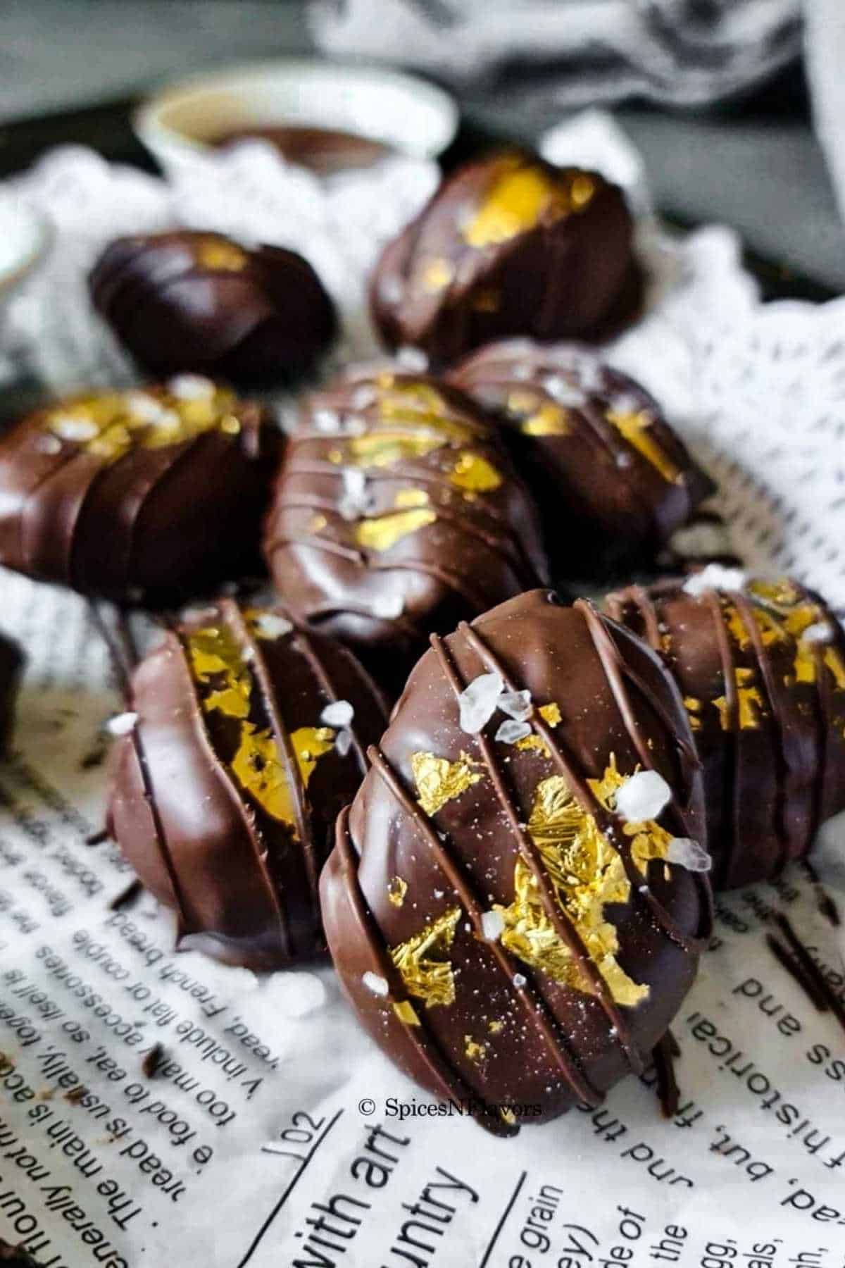 chocolate covered dates garnished with gold leaf, a drizzle of melted chocolate and sea salt