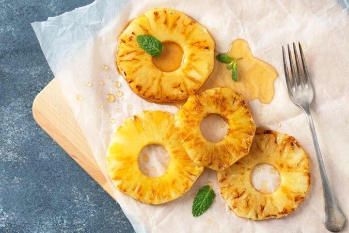 grilled pineapple slices placed on a parchment paper and drizzled with honey on top