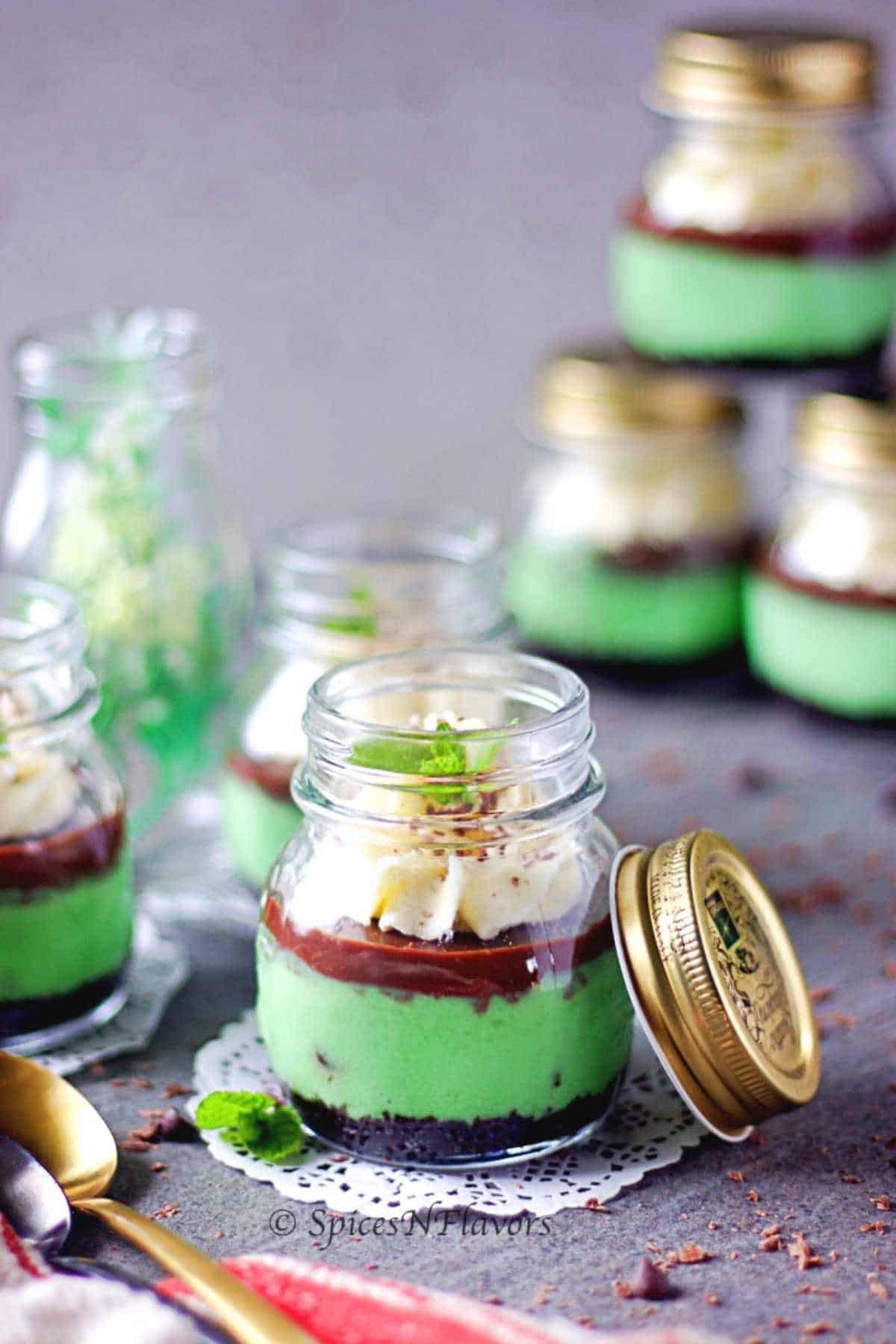 cute little mason jars filled with mint cheesecake and topped with chocolate ganache