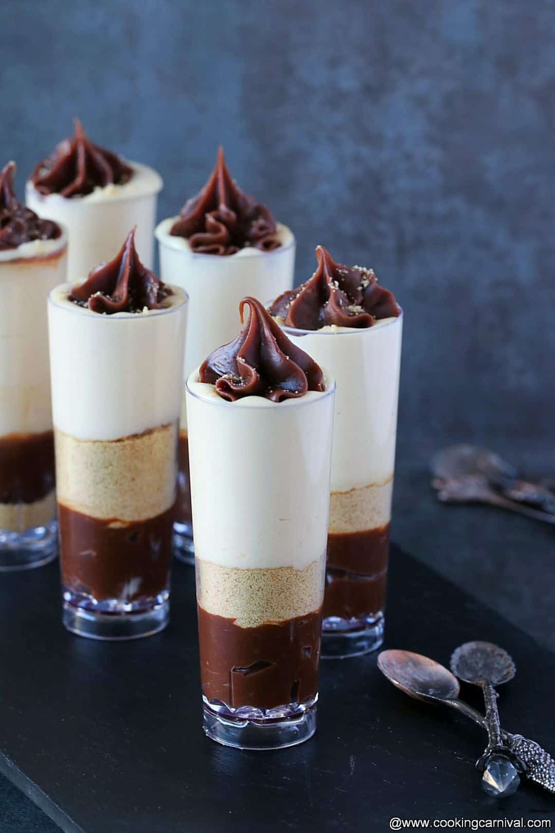 Mini cheesecakes assembled in tall glasses with caramel sauce and chocolate truffle sauce