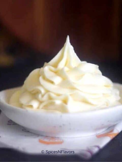 stiff cream cheese frosting piped on a small white bowl placed on a tissue paper