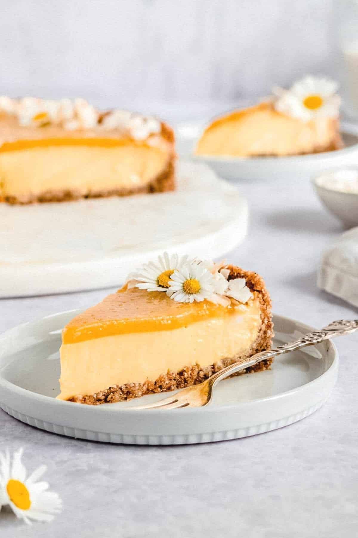 slice of vegan mango coconut cheesecake placed on a grey plate