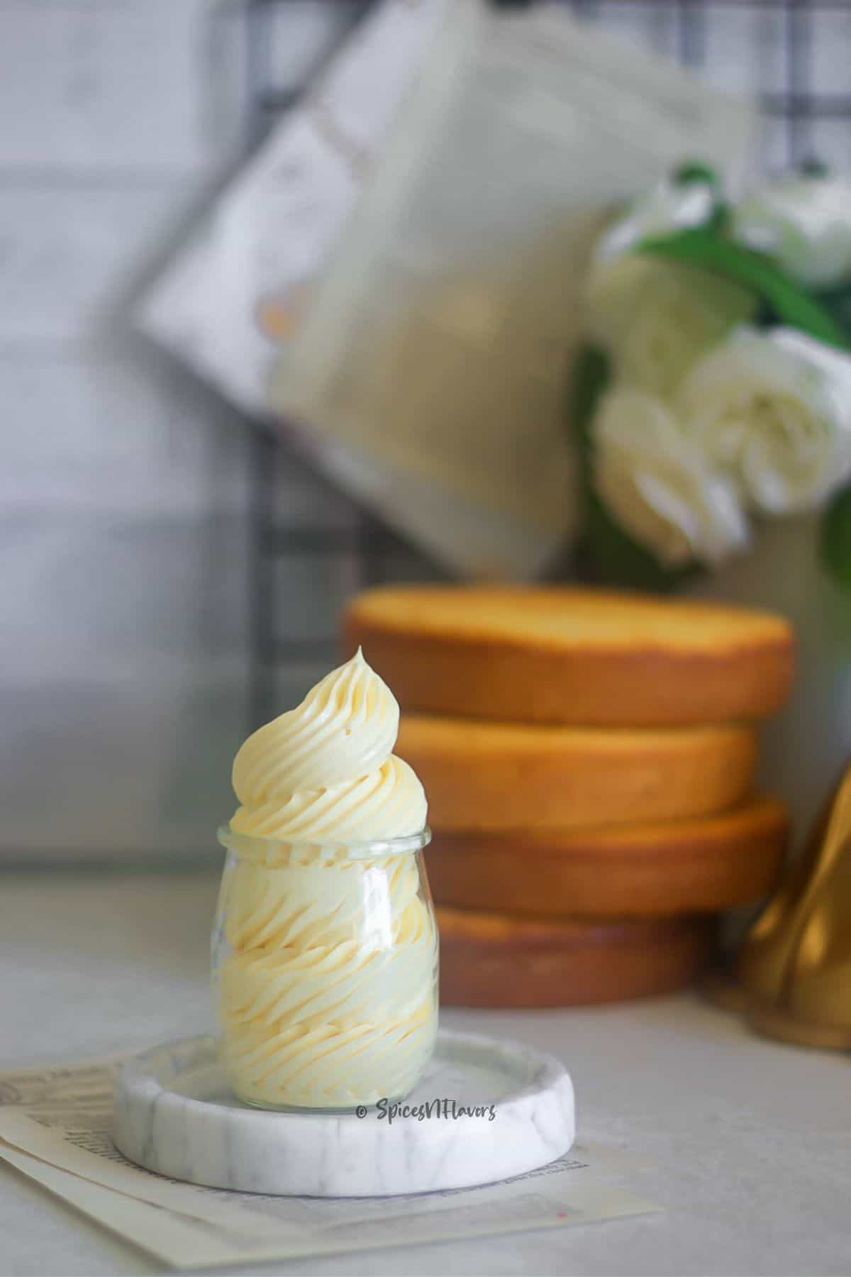 condensed milk buttercream piped in a glass jar placed on a marble stand