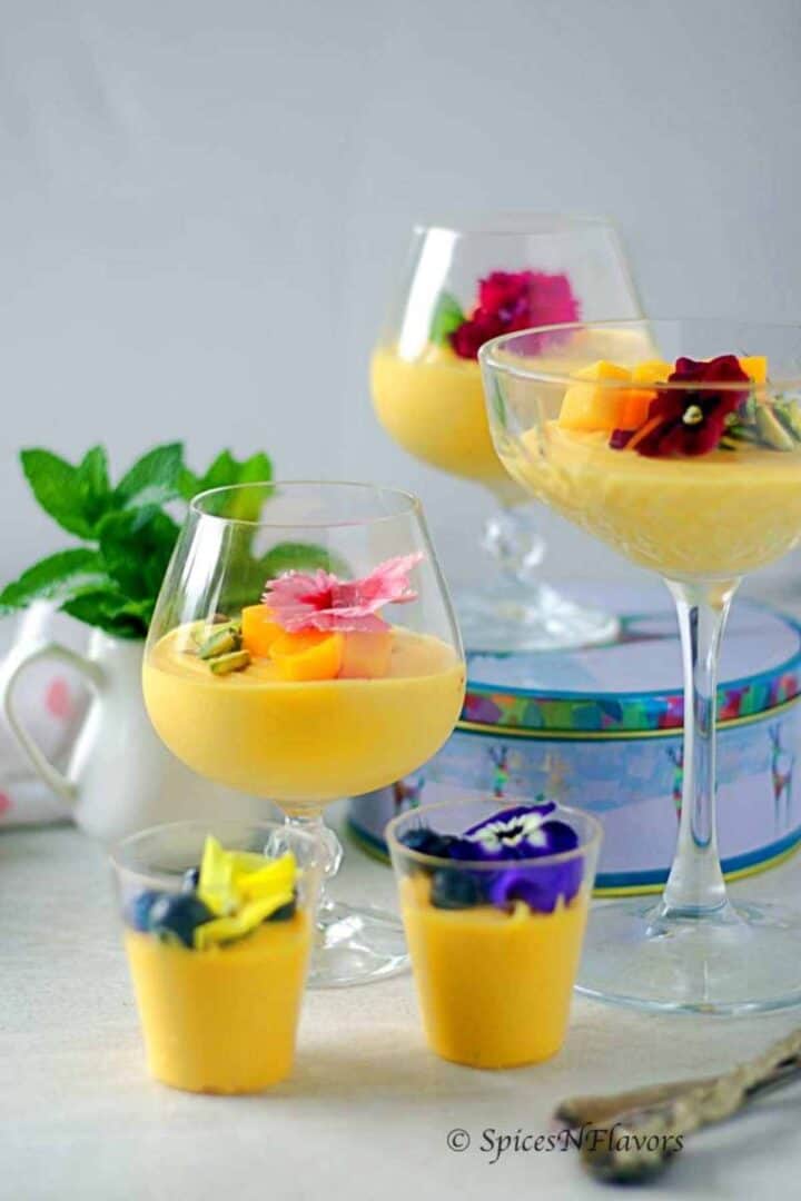 mango mousse served in wine and shot glasses and garnished with fresh flowers
