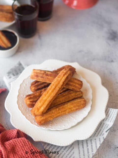 cinnamon coated golden brown churros placed on a white plate