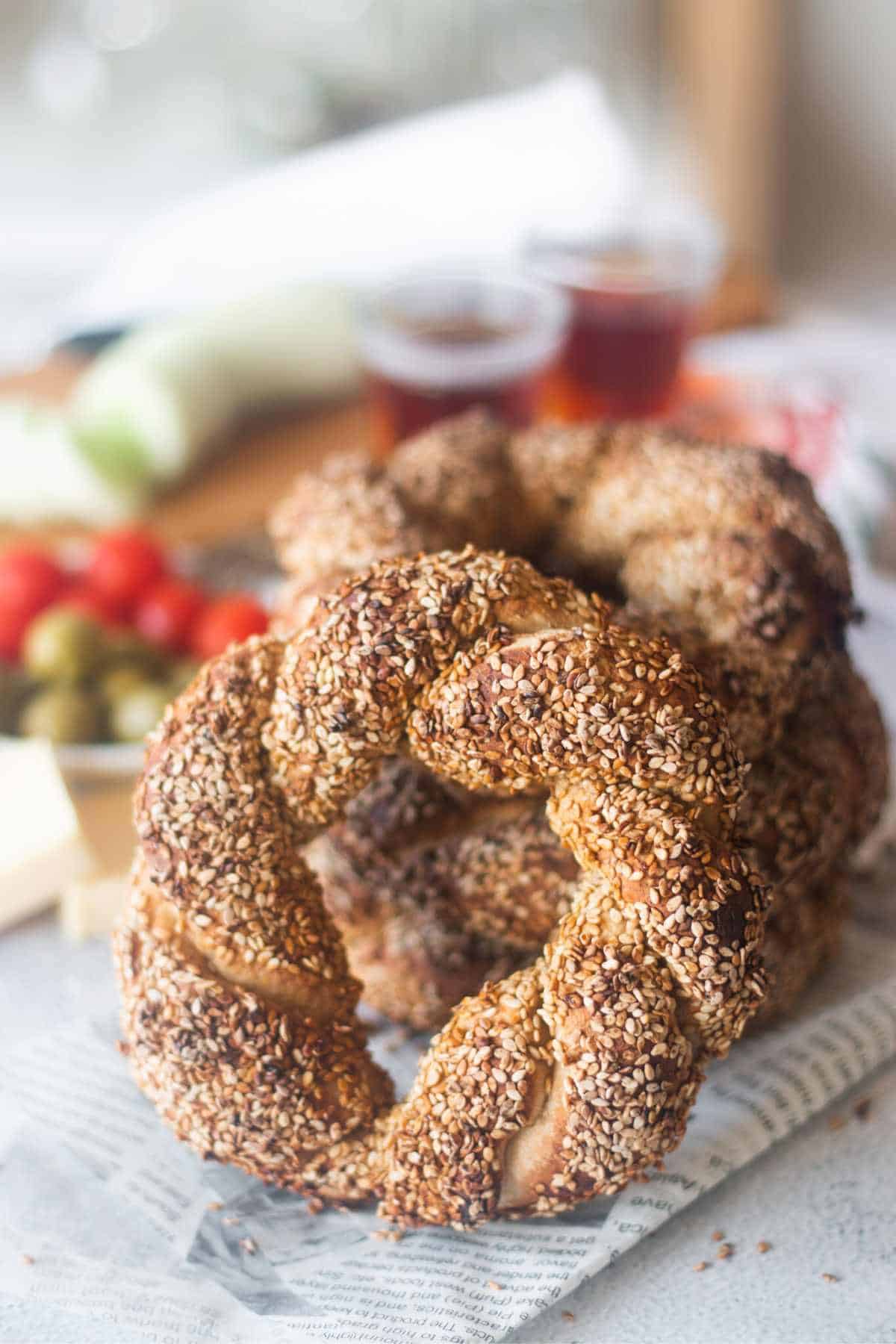 sesame crusted simit bread in the front with stacked bread behind it