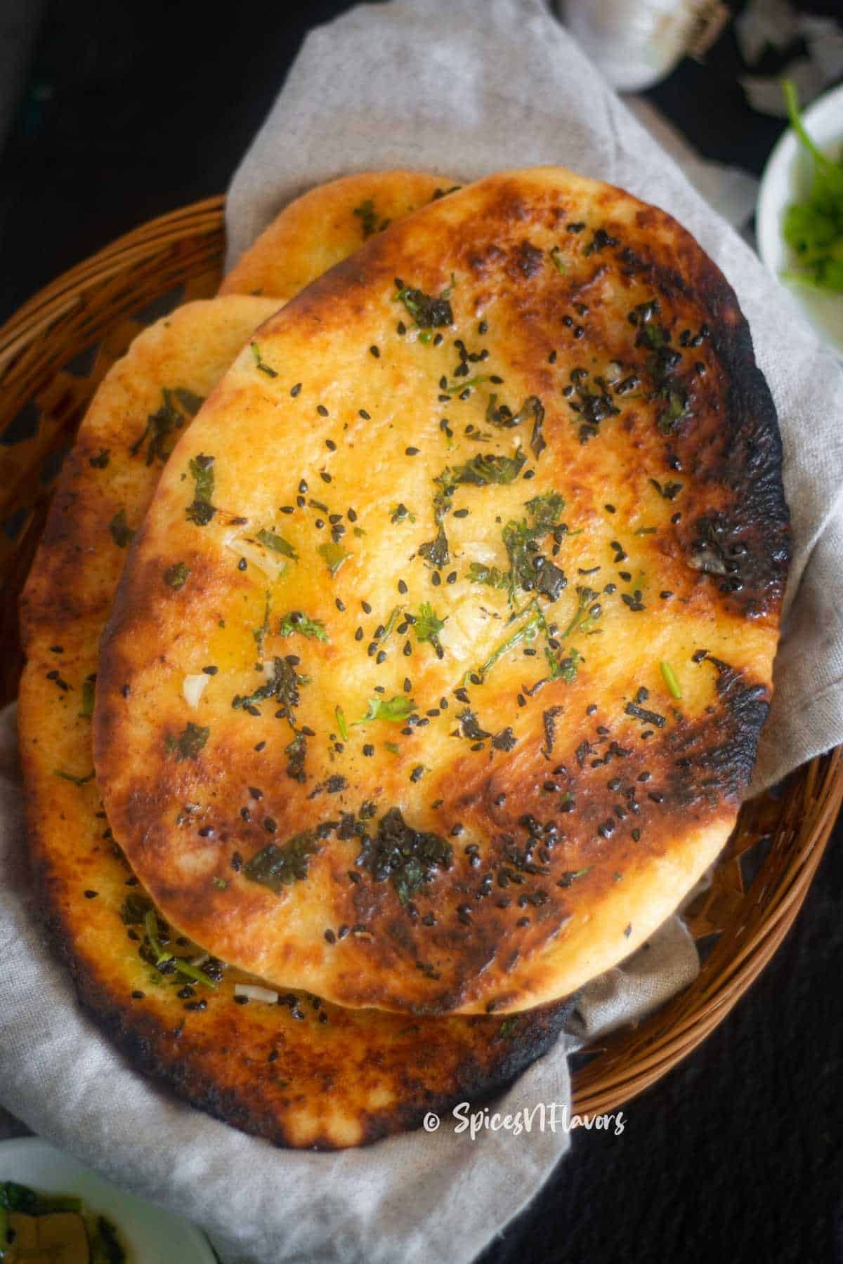 naan bread made in an air fryer is placed in a cane basket with a tea towel