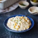 close up image of creamy corn casserole served on a blue plate for recipe card