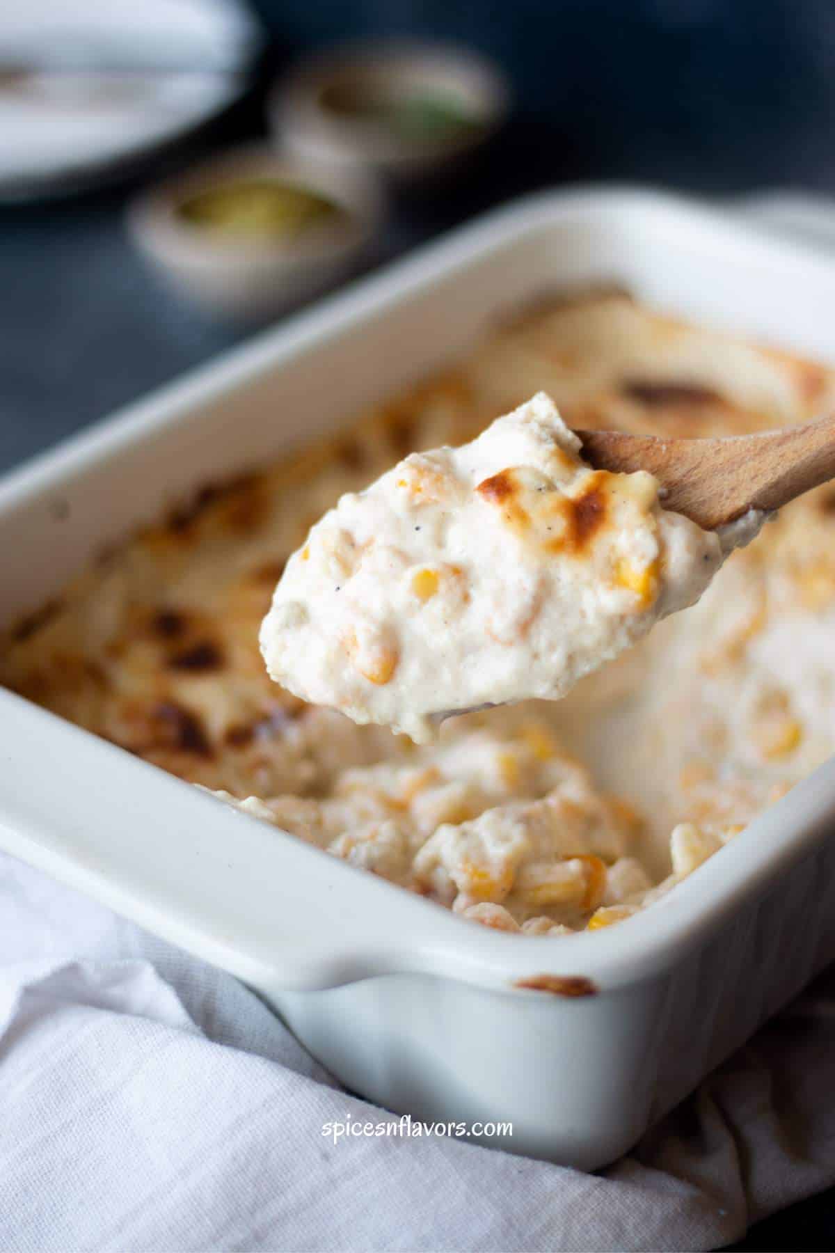 creamy corn casserole being scooped out using a wooden spoon