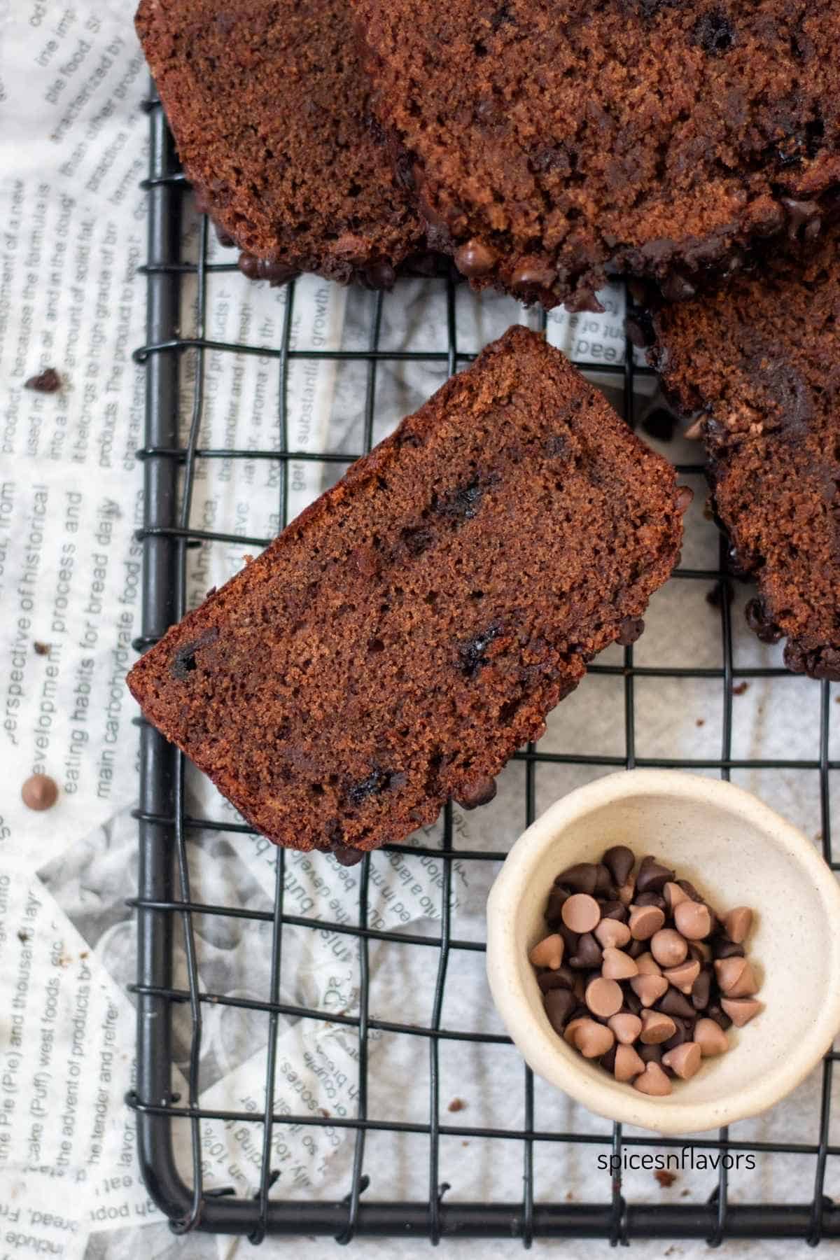 banana bread slice placed on wire rack with chocolate chips on the side
