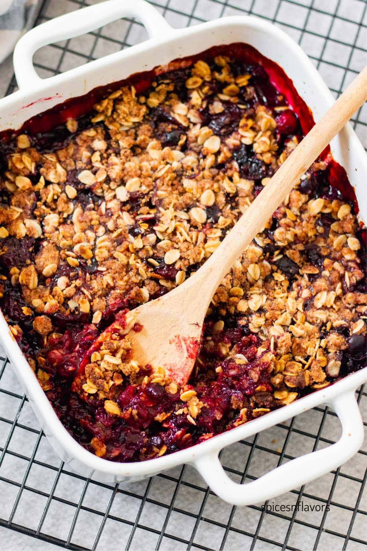 baked berry crisp with a  wooden ladle