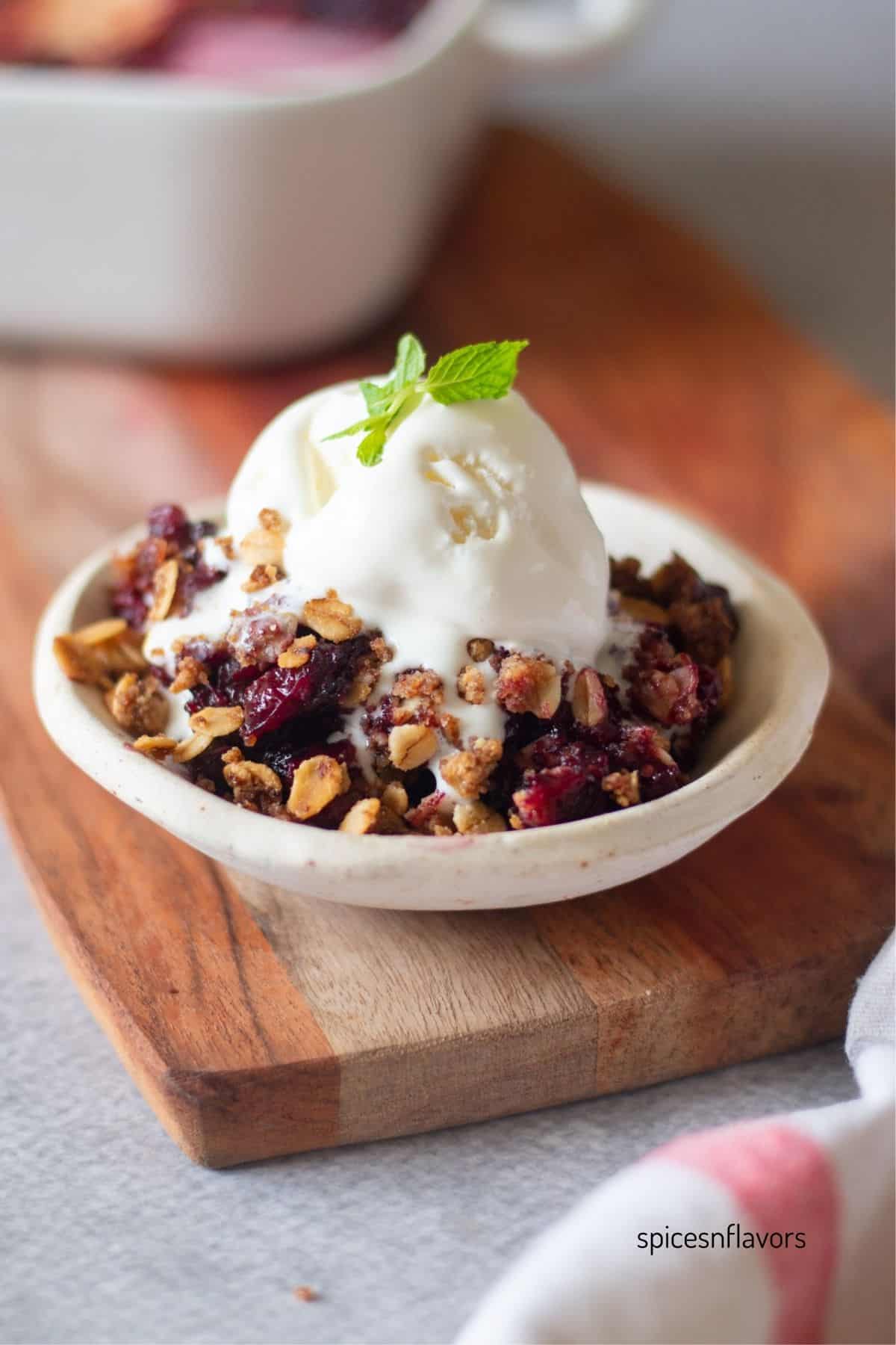 berry crisp served in a plate with ice cream on top