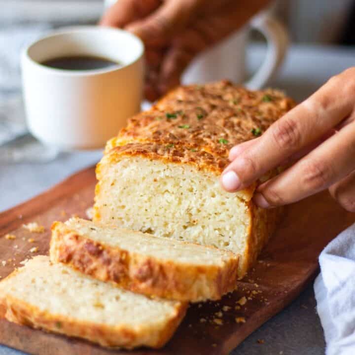 picking cheddar cheese bread with coffee on one hand