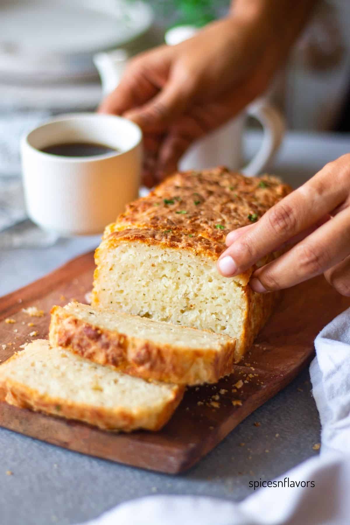 picking cheddar cheese bread with coffee on one hand