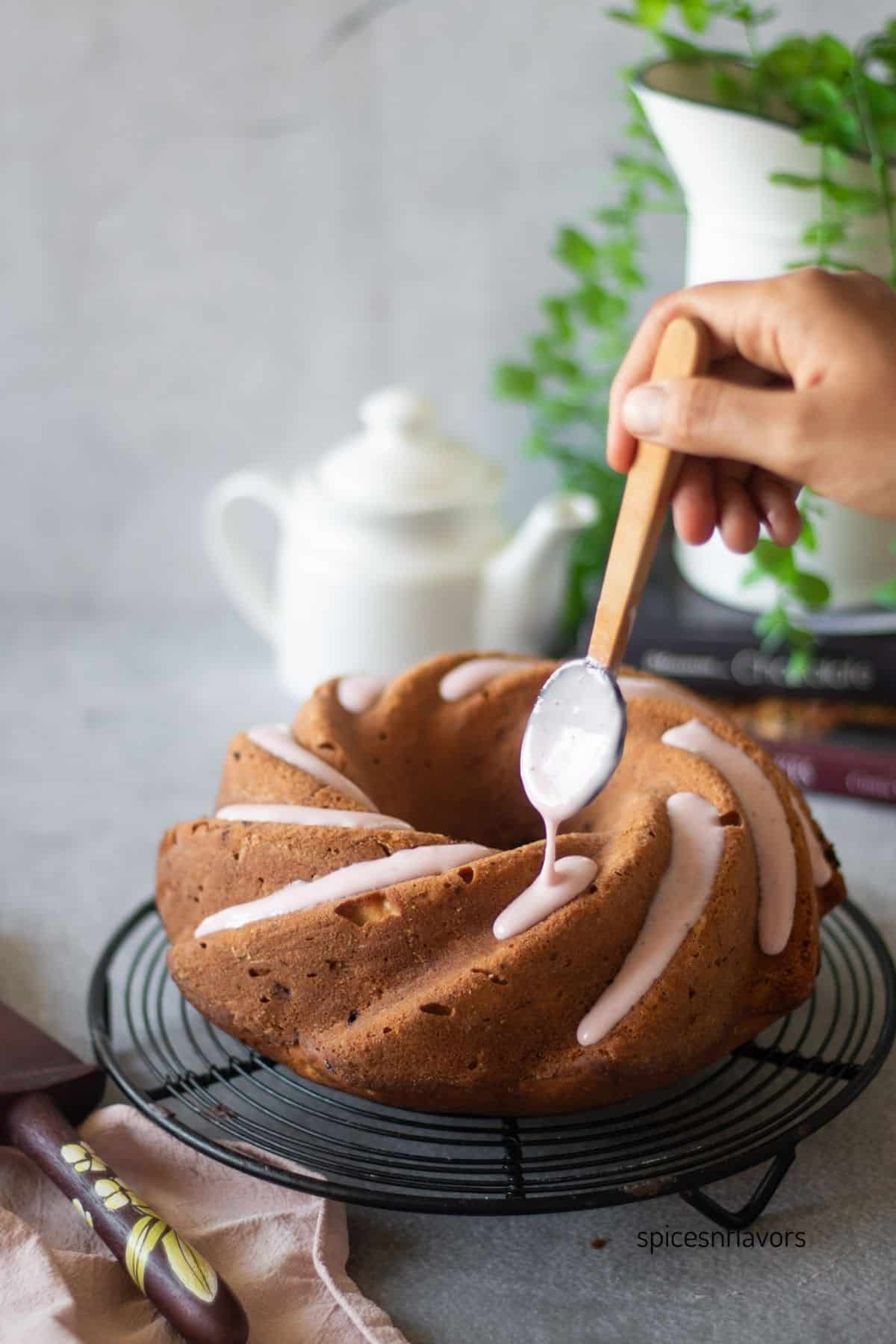 pouring strawberry glaze over strawberry pound cake