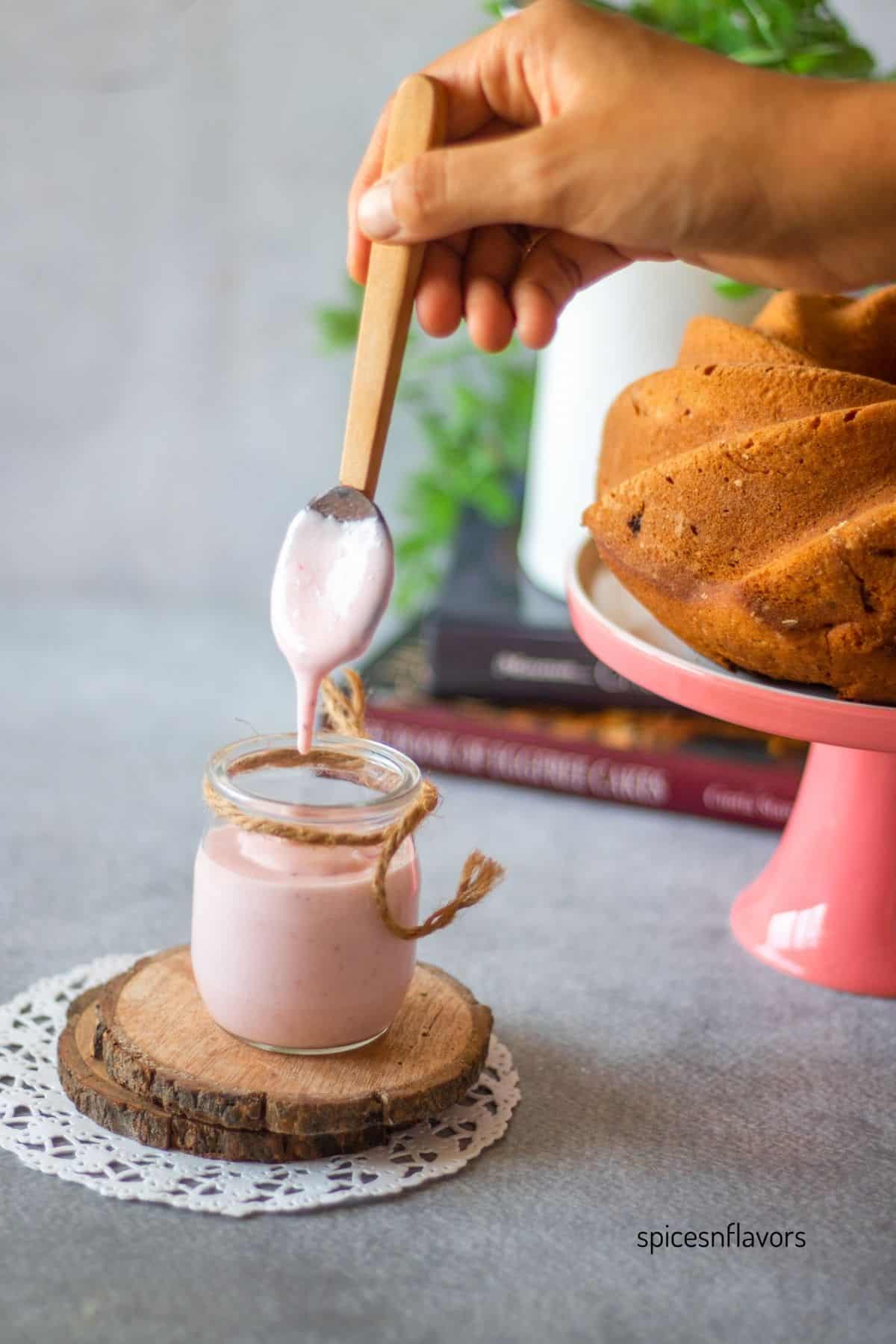 transferring strawberry glaze into a container using wooden spoon