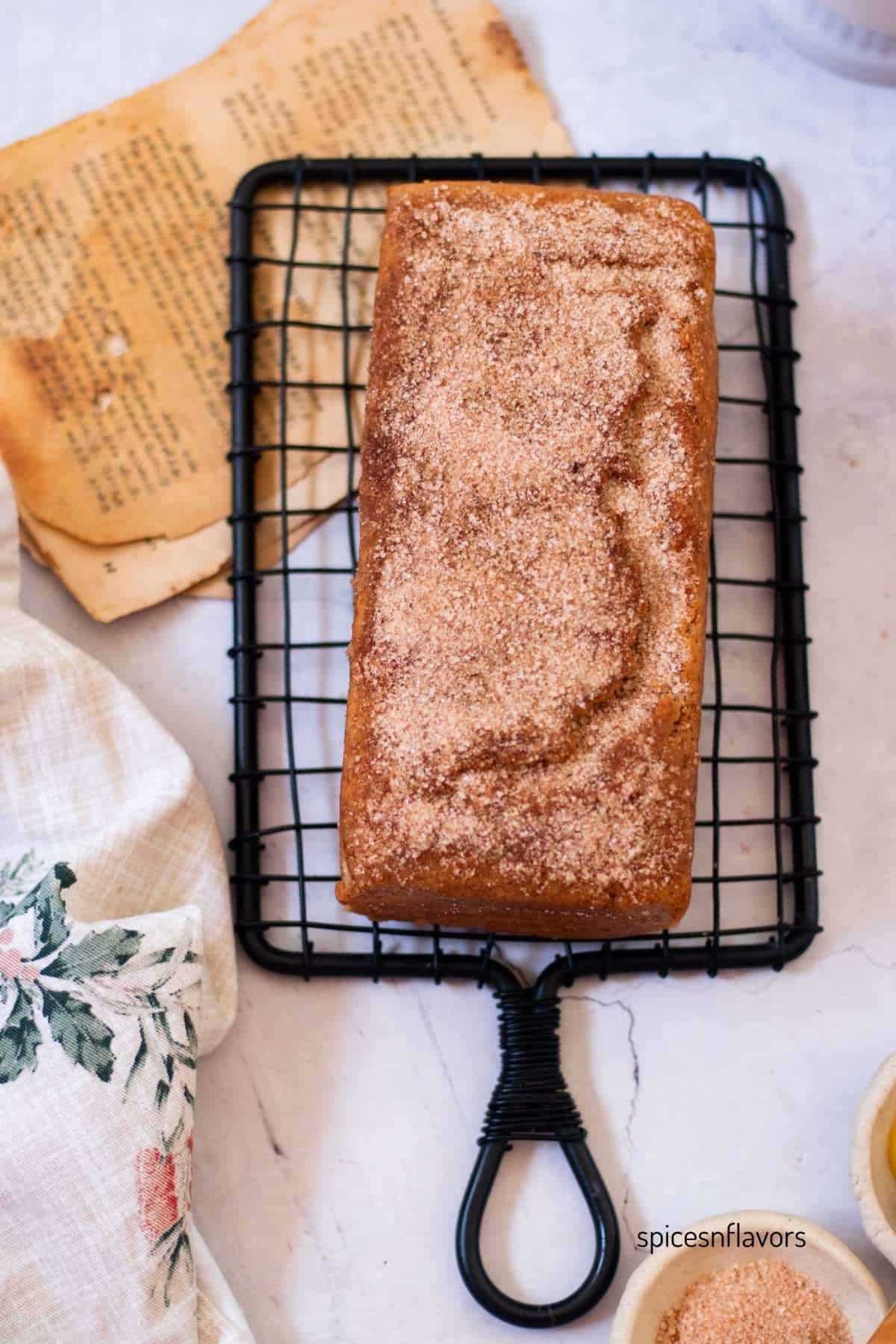 cinnamon donut bread on wire rack with tea towel on side