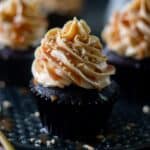 close up image of single frosted coffee cupcake placed on baking tray