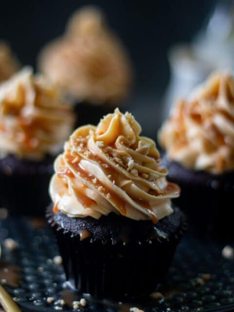 one coffee cupcake frosted with caramel frosting in centre with three cupcakes in the background