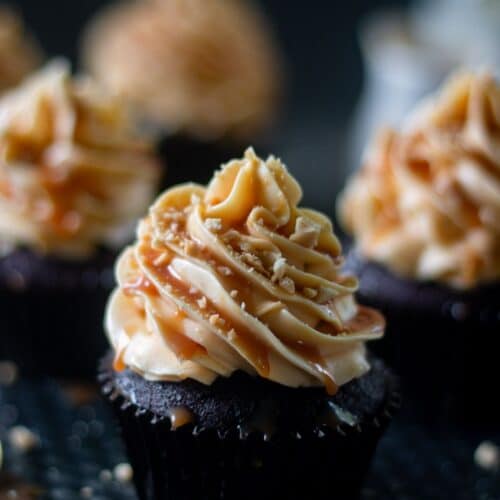 one coffee cupcake frosted with caramel frosting in centre with three cupcakes in the background