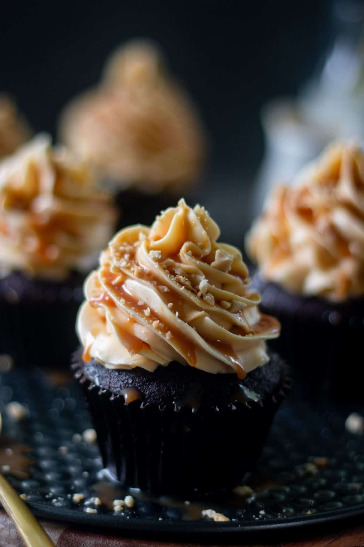 one coffee cupcake frosted with caramel frosting in centre with three cupcakes in the background