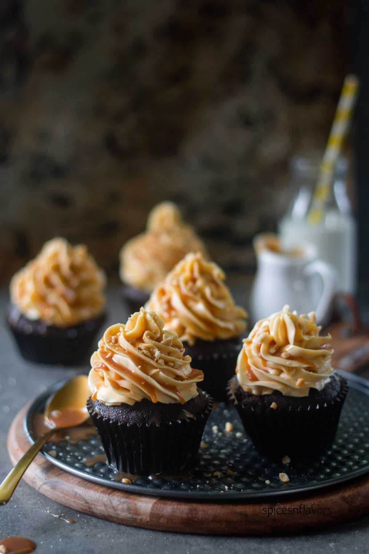 5 coffee cupcakes frosted with caramel frosting placed on a wooden board