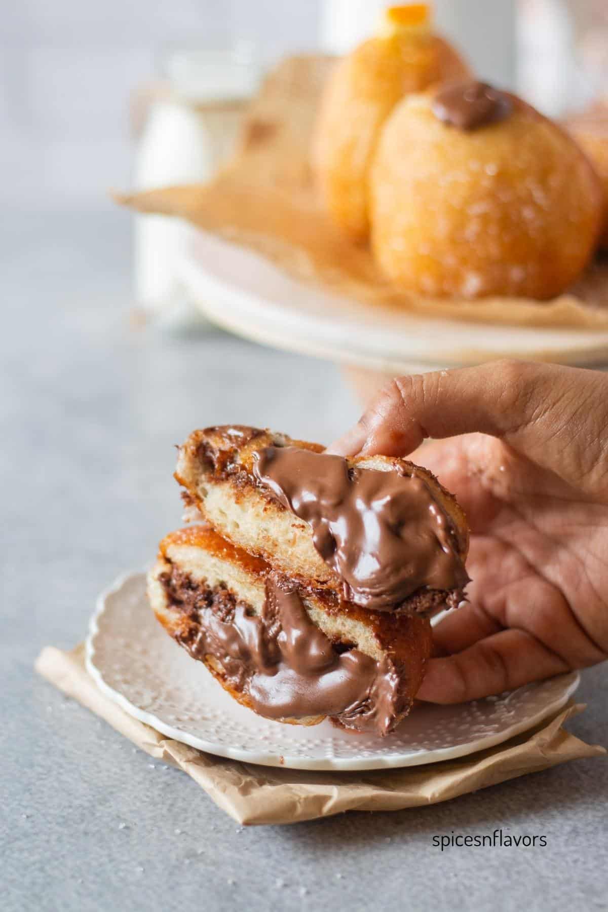italian bombolonis held in hands with nutella filling oozing out