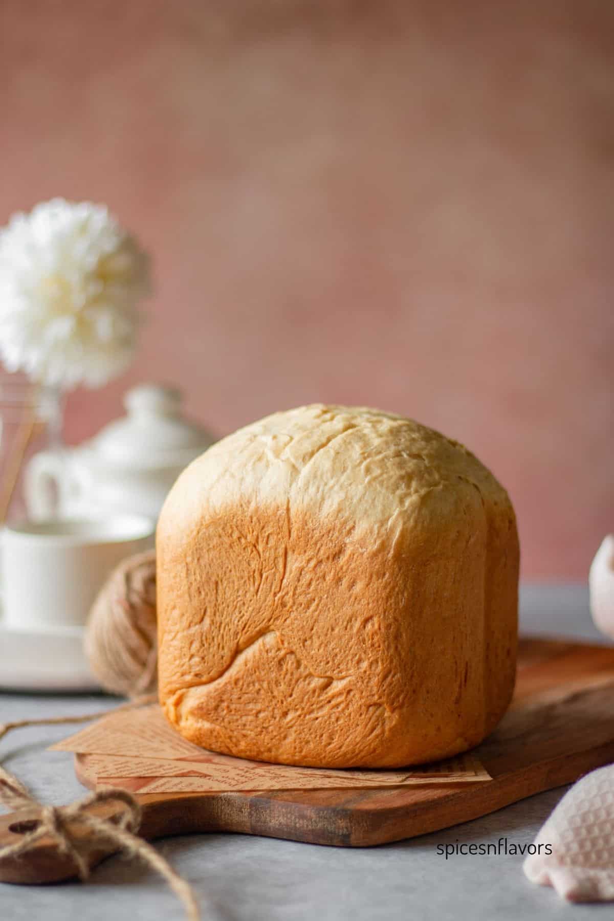 whole loaf of japanese milk bread made in bread machine placed on a wooden board