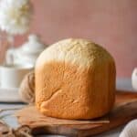 whole loaf of japanese milk bread baked in bread machine placed on wooden board