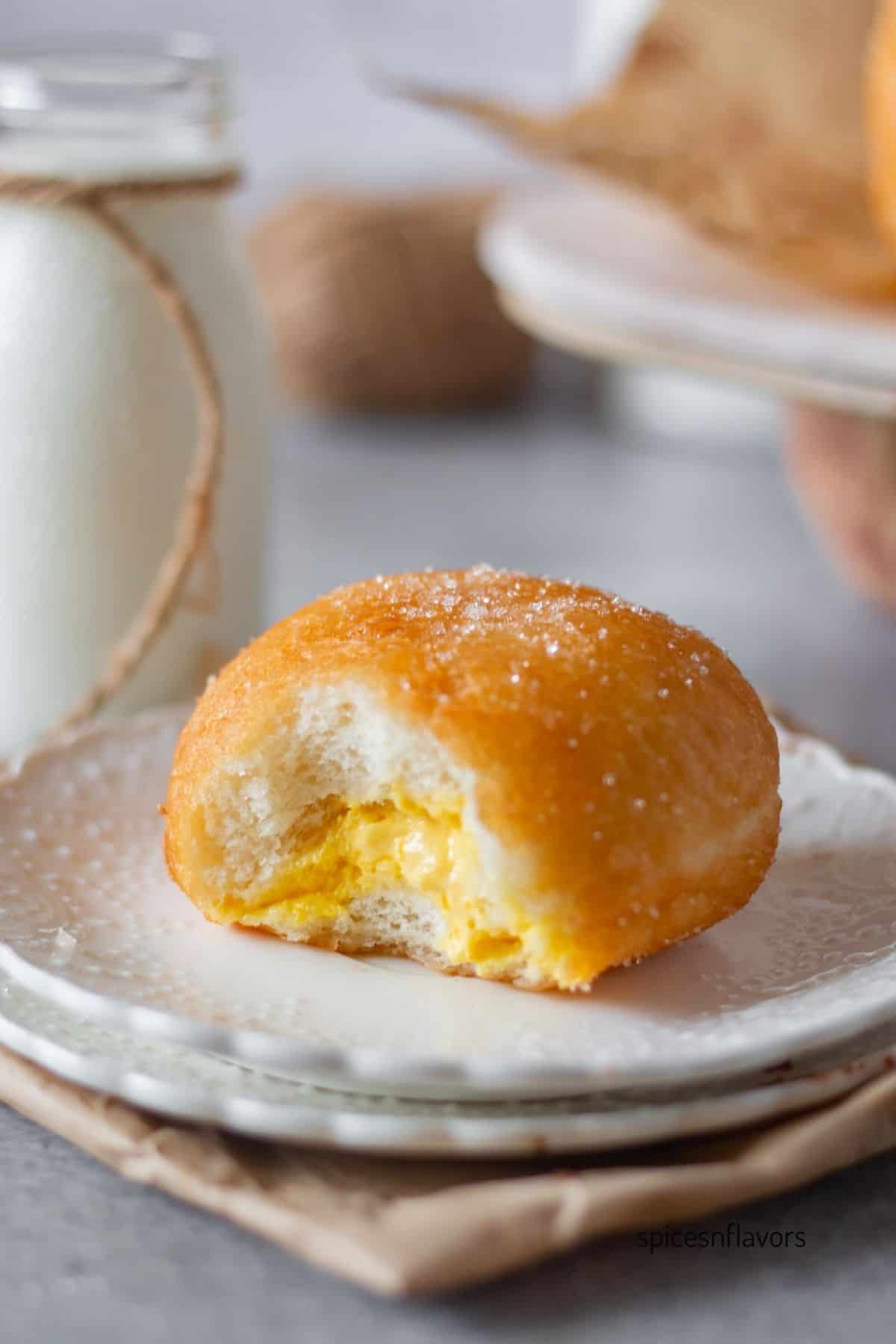 a small bite taken from cream doughnuts then placed on a white plate