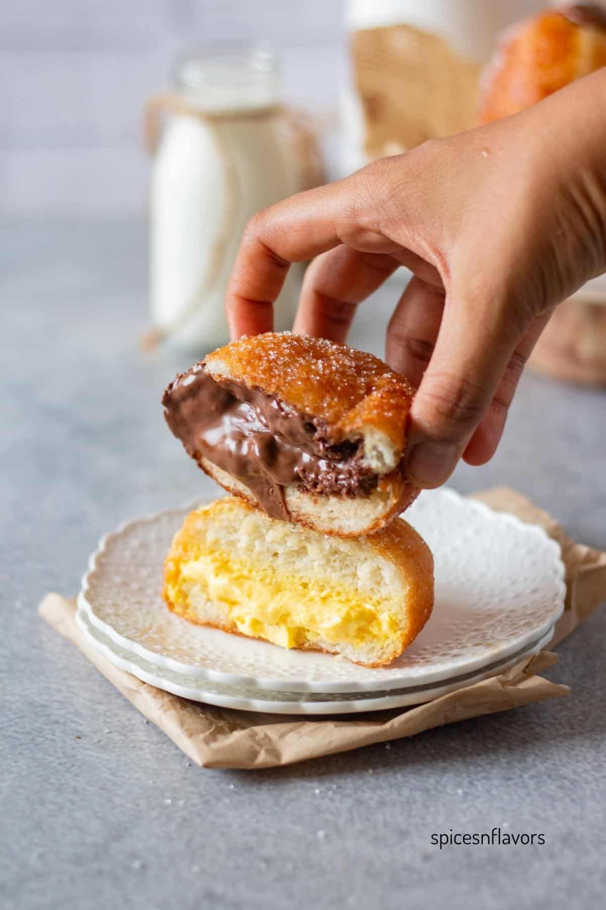 picking up sliced doughnuts that has been filled with mango cream and nutella