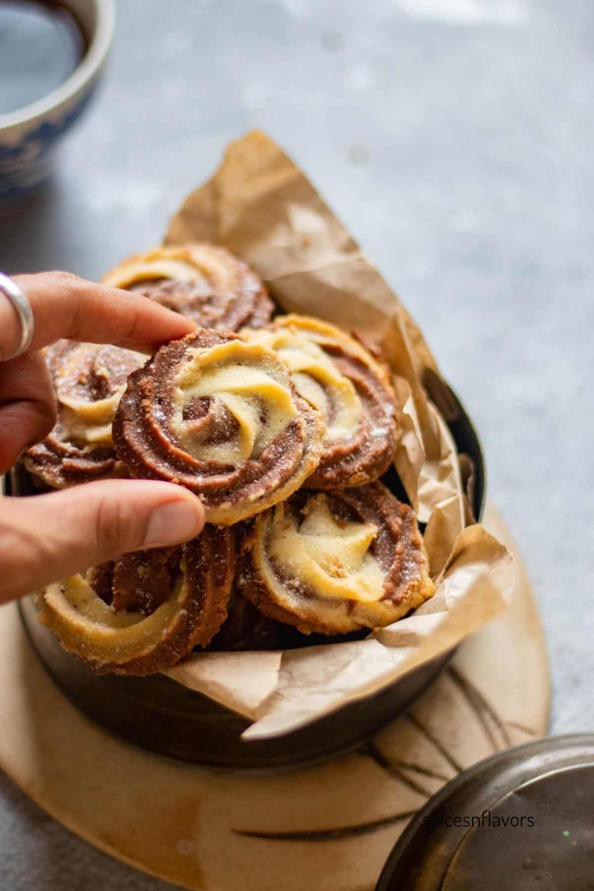 picking up a chocolate vanilla swirl cookie with fingers